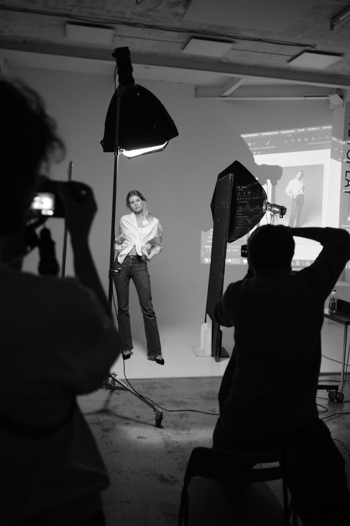 Black and white shot of a model in a professional photo studio with photographers.